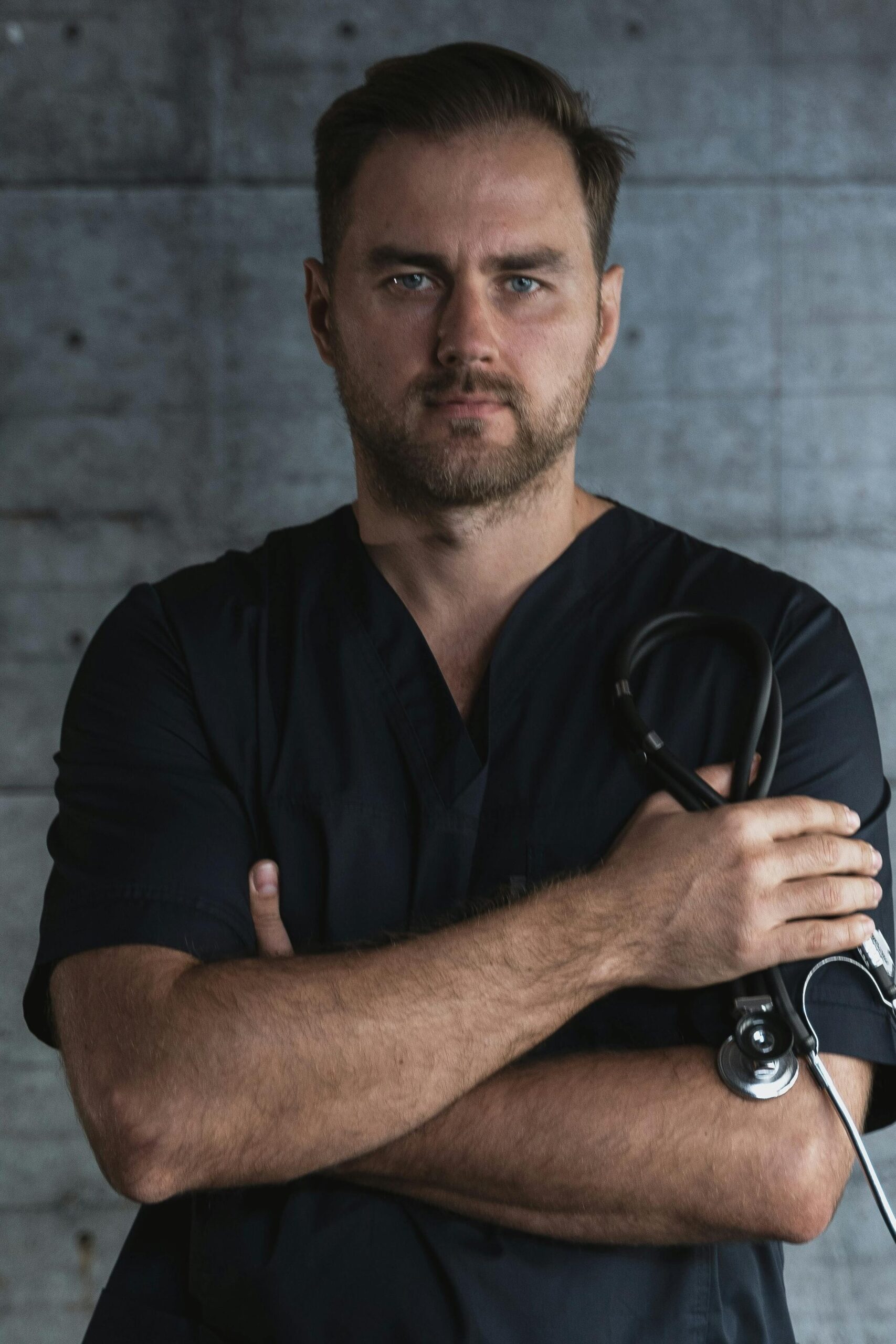 Portrait of a confident doctor standing with a stethoscope against a plain background, symbolizing medical professionalism.